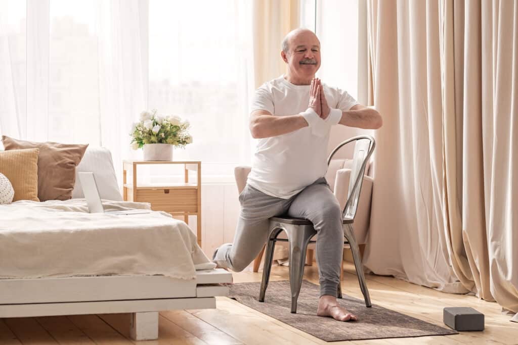 Older adult doing physical low-impact exercises in his senior living apartment