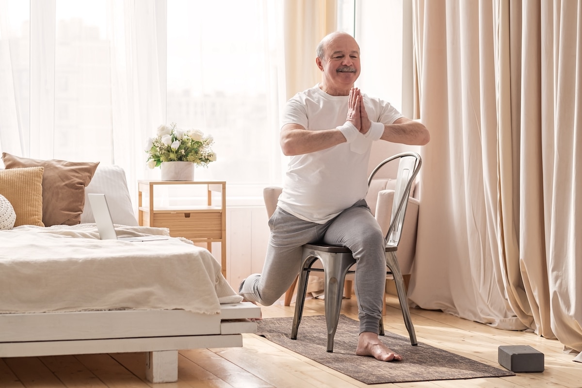 Older adult doing physical low-impact exercises in his senior living apartment