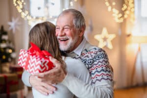 Happy senior receiving a holiday gift from his adult daughter